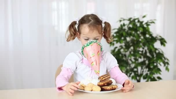 Menina sentada em uma mesa com biscoitos . — Vídeo de Stock