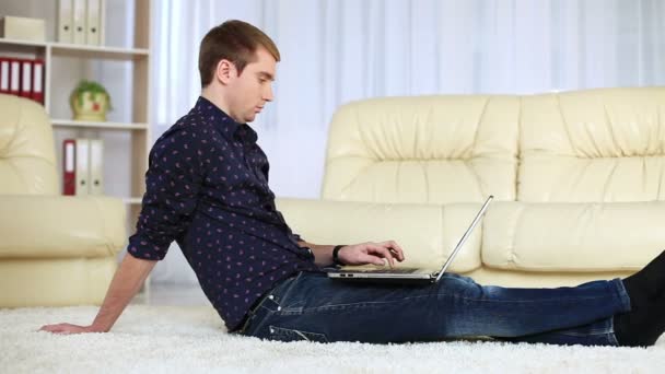 Mann sitzt mit Laptop auf Teppich. — Stockvideo