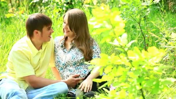 Женщина и мужчина сидят в траве — стоковое видео