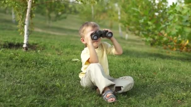 Маленький хлопчик з біноклями сидить — стокове відео