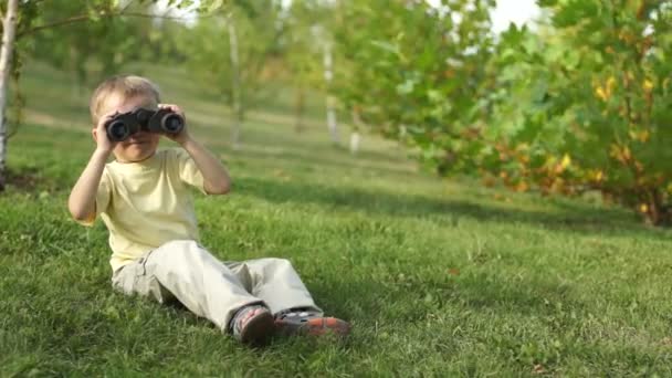 Kleiner Junge mit Fernglas sitzt — Stockvideo