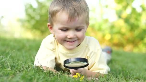 Menino com uma lupa deitado — Vídeo de Stock