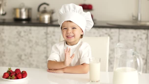 Pequeno menino chef sentado à mesa — Vídeo de Stock