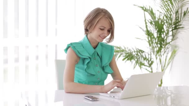 Mujer sentada en el escritorio usando laptop — Vídeos de Stock