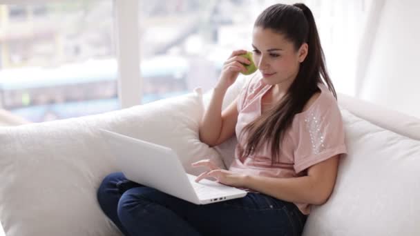 Meisje, zittend op de Bank met behulp van laptop — Stockvideo