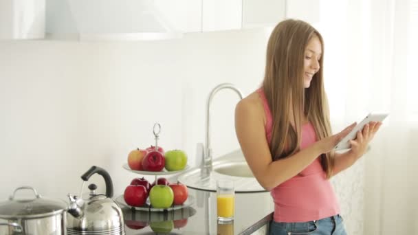 Menina de pé na cozinha usando touchpad — Vídeo de Stock