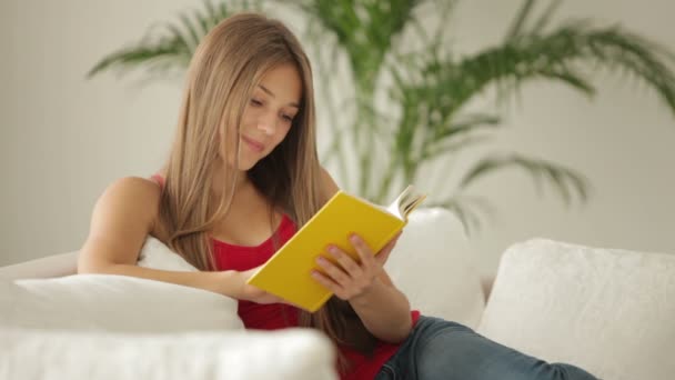 Mujer sentada en el sofá leyendo — Vídeos de Stock