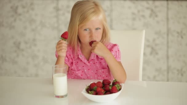 Meisje zitten aan tafel eten aardbeien — Stockvideo