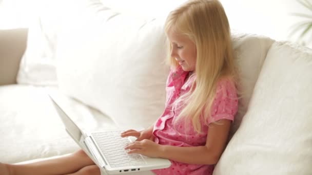 Дівчина сидить на дивані з ноутбуком — стокове відео