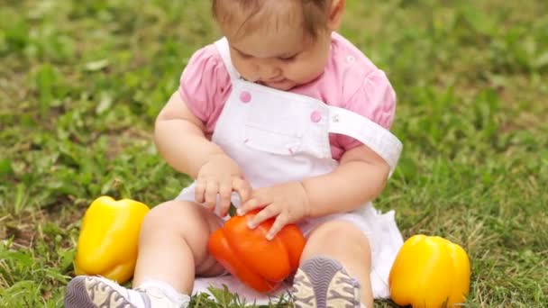 Smiling baby girl with peppers. — Stock Video