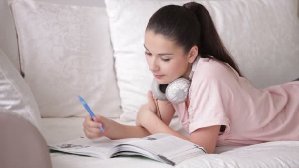 Girl in headset lying on sofa — Stock Video