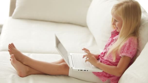 Chica sentada en el sofá utilizando el ordenador portátil — Vídeos de Stock