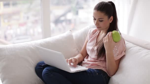 Flicka sitter på soffan med laptop — Stockvideo