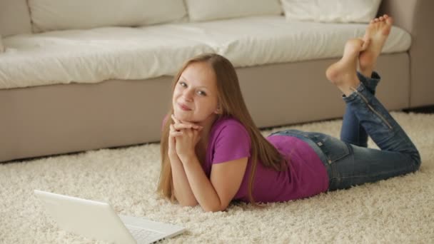 Chica acostada en la alfombra con portátil — Vídeos de Stock
