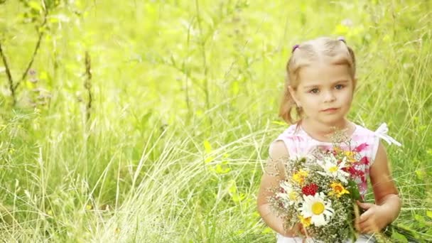 Kleines Mädchen auf Gras mit Blumen. — Stockvideo