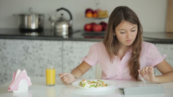 Dívka sedí u stolu jíst salát — Stock video