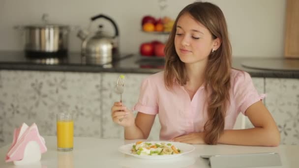 Девушка сидит за столом и ест салат — стоковое видео