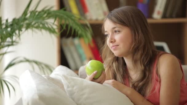 Flicka avkopplande på soffa äta äpple — Stockvideo