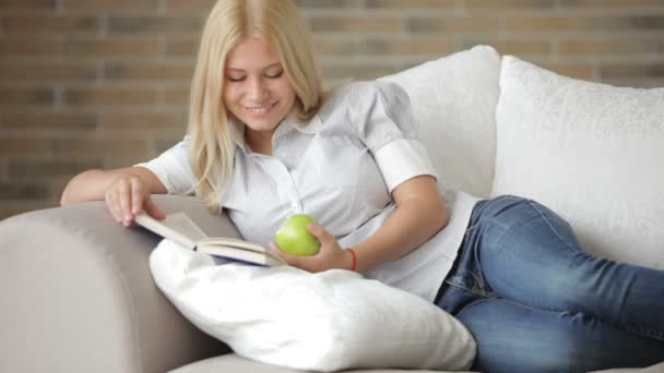 Chica acostada en sofá lectura — Vídeos de Stock