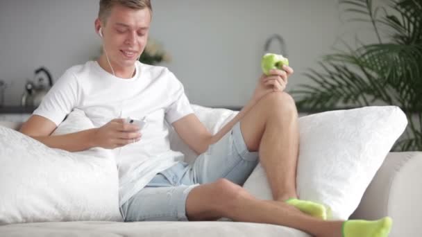 Man ontspannen op de sofa met cellphone — Stockvideo