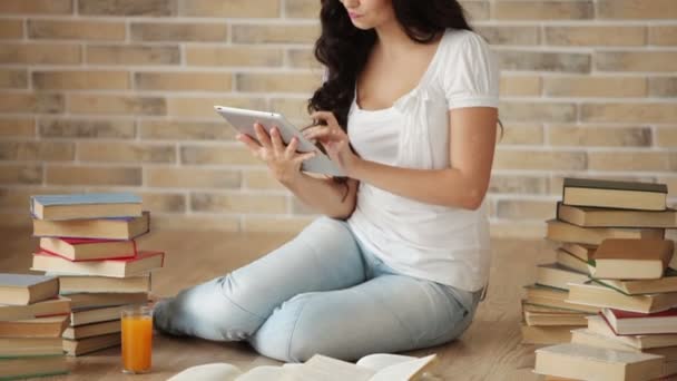 Girl sitting on floor with pile of books — Stock Video