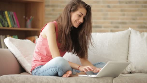 Menina sentada no sofá usando laptop — Vídeo de Stock