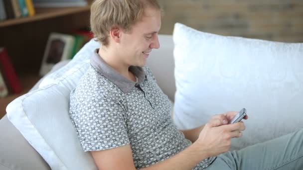 Chico relajante en sofá usando celular pone — Vídeos de Stock