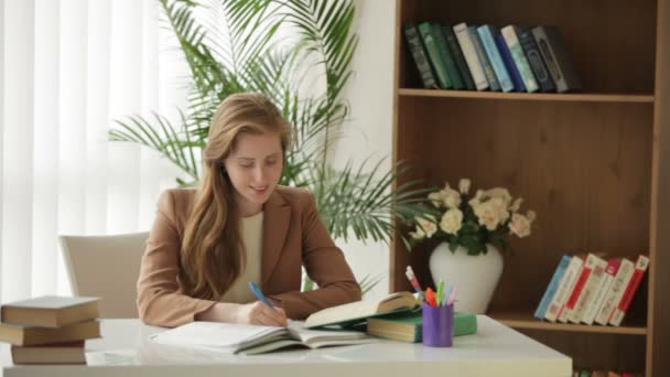 Meisje zit aan bureau met boeken — Stockvideo