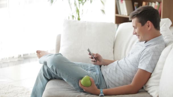 Man sitter på soffan med hjälp av mobiltelefon — Stockvideo