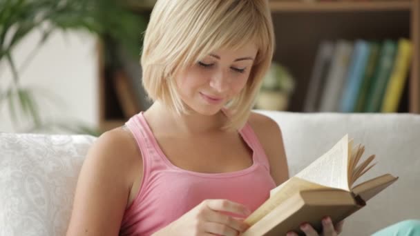 Mujer joven relajándose en el sofá con libro — Vídeos de Stock