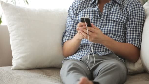 Человек сидит на диване и слушает музыку — стоковое видео
