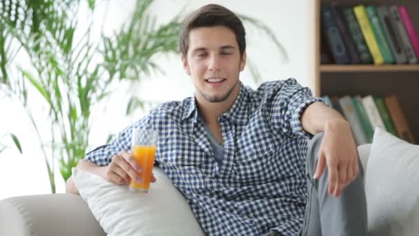 Mann sitzt auf Couch und trinkt Saft — Stockvideo
