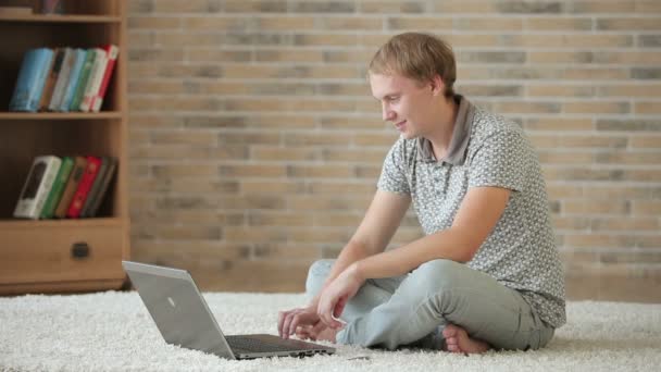 Facet siedzi na podłodze przy użyciu laptopa — Wideo stockowe
