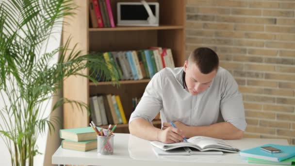 Studentin sitzt am Tisch und schreibt — Stockvideo