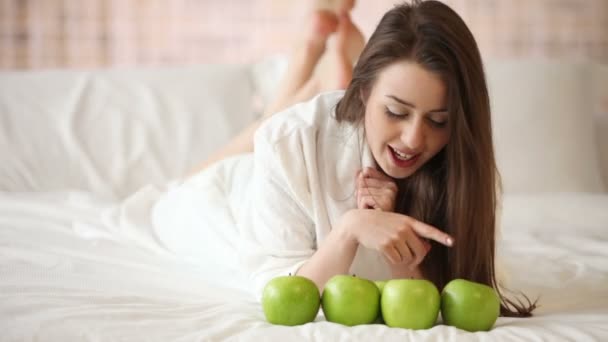 Chica acostada en la cama con manzanas — Vídeos de Stock