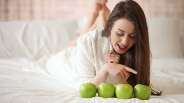 Chica acostada en la cama con manzanas — Vídeo de stock