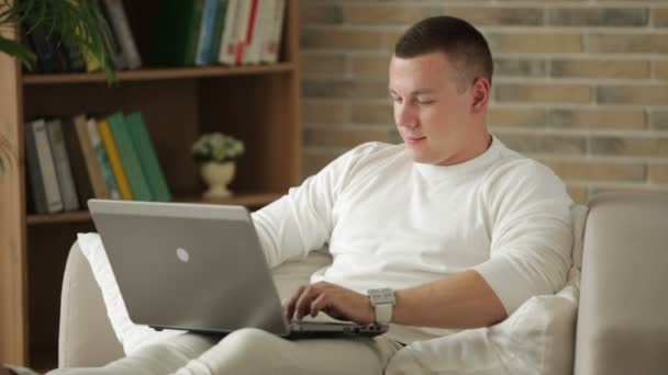 Ragazzo seduto sul divano utilizzando il computer portatile — Video Stock