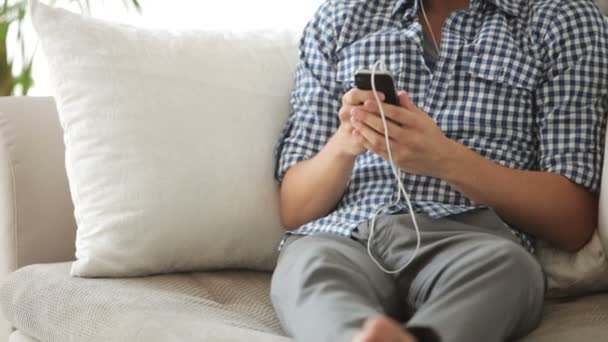 Man ontspannen op de sofa en luisteren naar muziek — Stockvideo