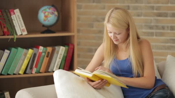 Dziewczyna siedzi na kanapie czytania książki — Wideo stockowe