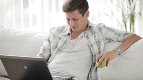 Man sitter på soffan med laptop — Stockvideo