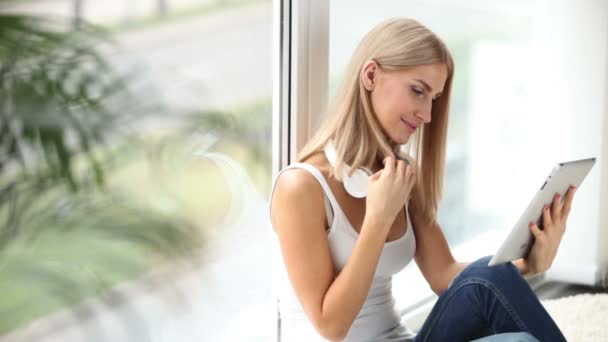 Flicka sitter av fönster med pekplatta — Stockvideo