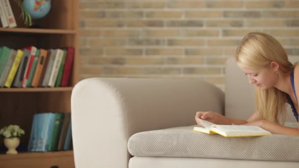 Dziewczynka leżąc na kanapie czytanie książki — Wideo stockowe