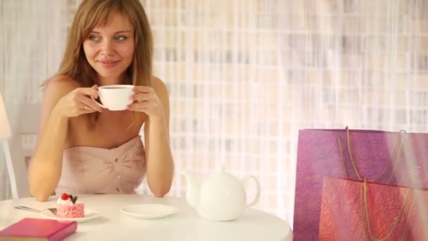 Chica sentada en la cafetería bebiendo té — Vídeos de Stock