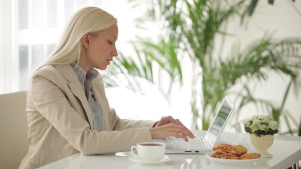 Mujer sentada en la mesa usando portátil — Vídeos de Stock