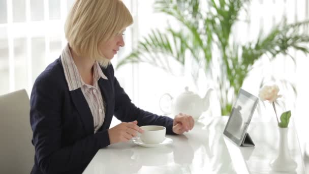 Femme d'affaires au bureau en utilisant touchpad boire du thé — Video