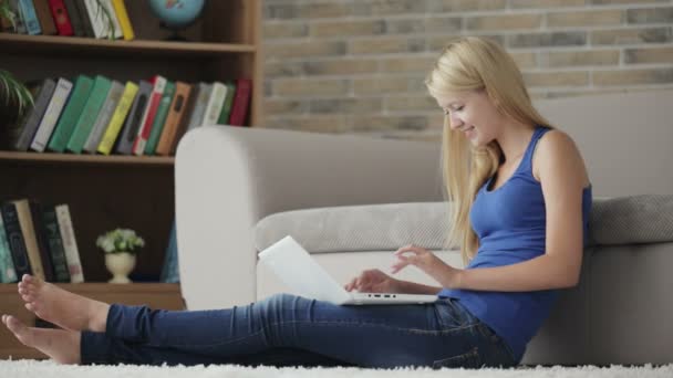 Girl sitting on carpet using laptop — Stock Video