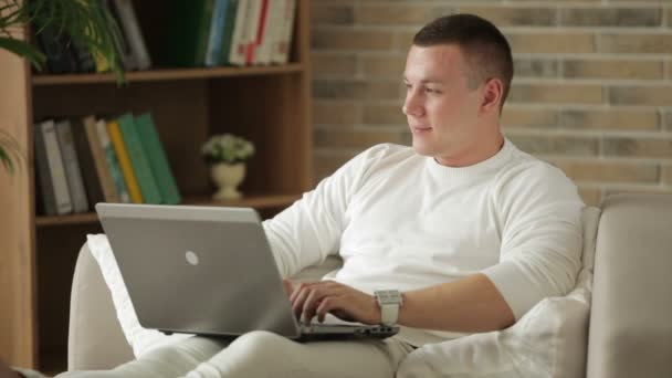 Uomo seduto sul divano e utilizzando il computer portatile . — Video Stock