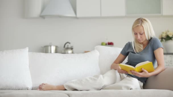 Дівчина розслабляється на дивані читання — стокове відео