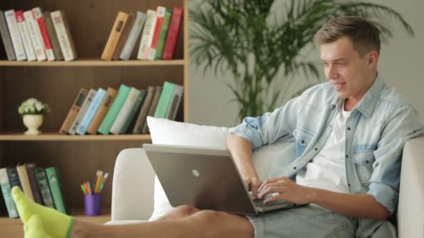 Killen sitter på soffan och använder bärbar dator. — Stockvideo