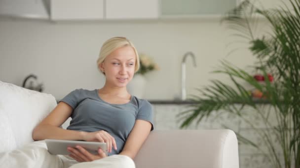 Woman sitting on sofa with touchpad — Stock Video